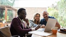 A financial adviser works with a smiling couple outside on their patio.