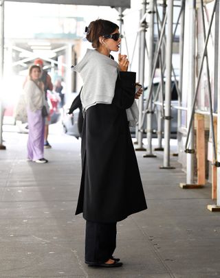 Kaia Gerber wears a black hair clip with a black trench coat trousers and ballet flats in new york city