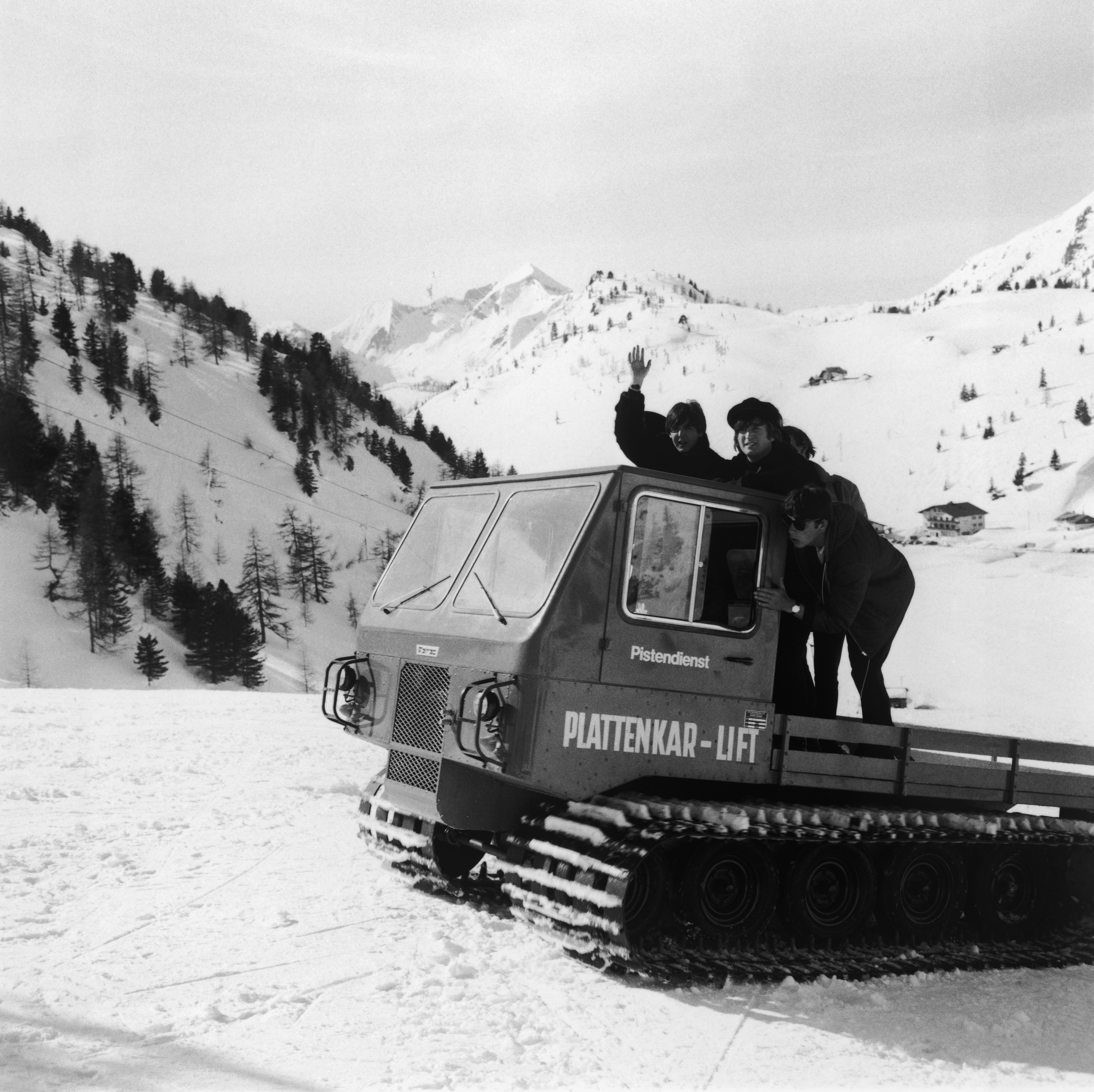 Paul McCartney and John Lennon on a vehicle with caterpillar tracks in the snowy Austrian Alps during the making of the second Beatles film 'Help!'