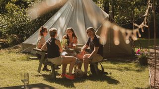 A group of people sit at a picnic table next to a yurt