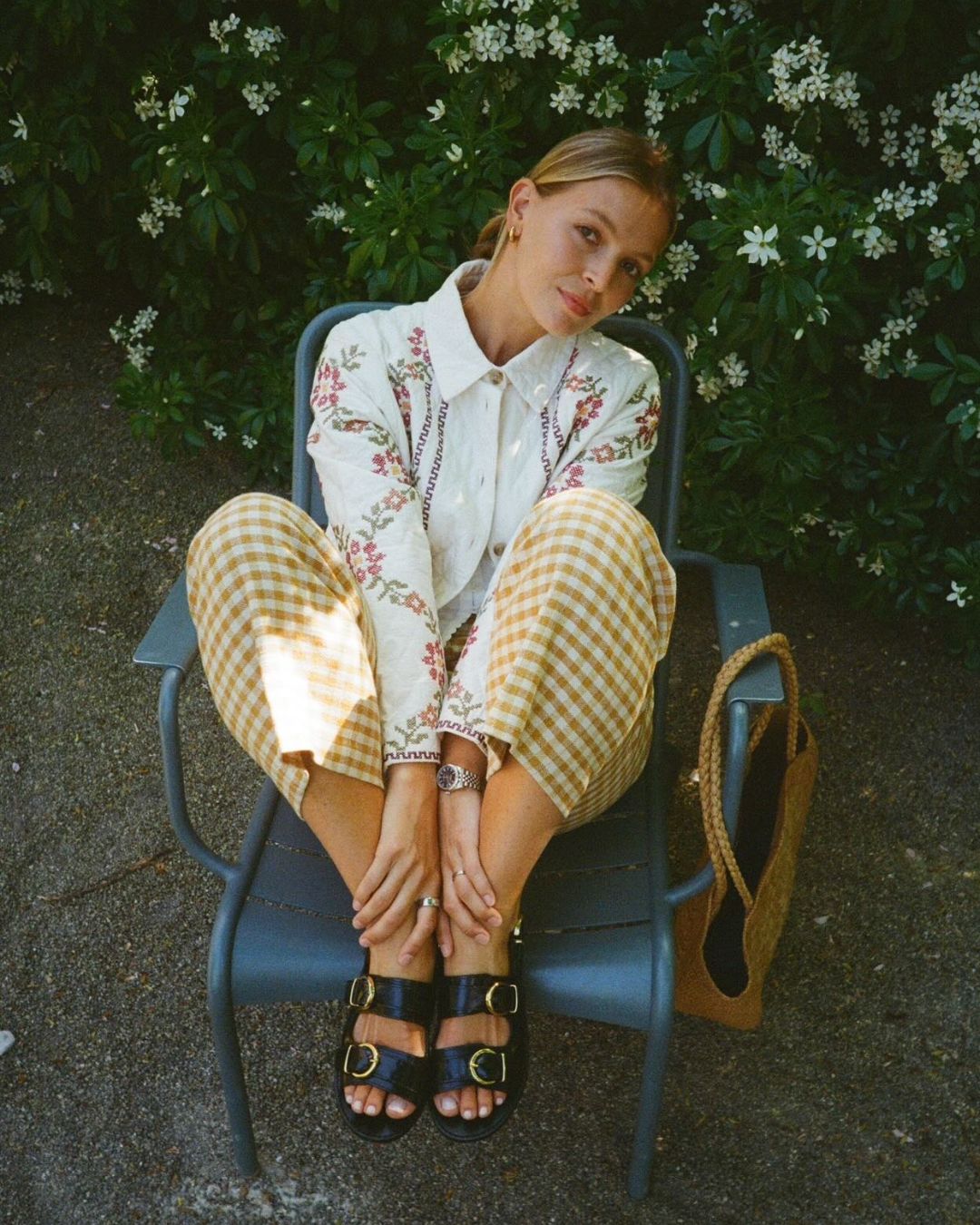 Influencer wears yellow gingham trousers with a white embroidered blouse and black strappy sandals.