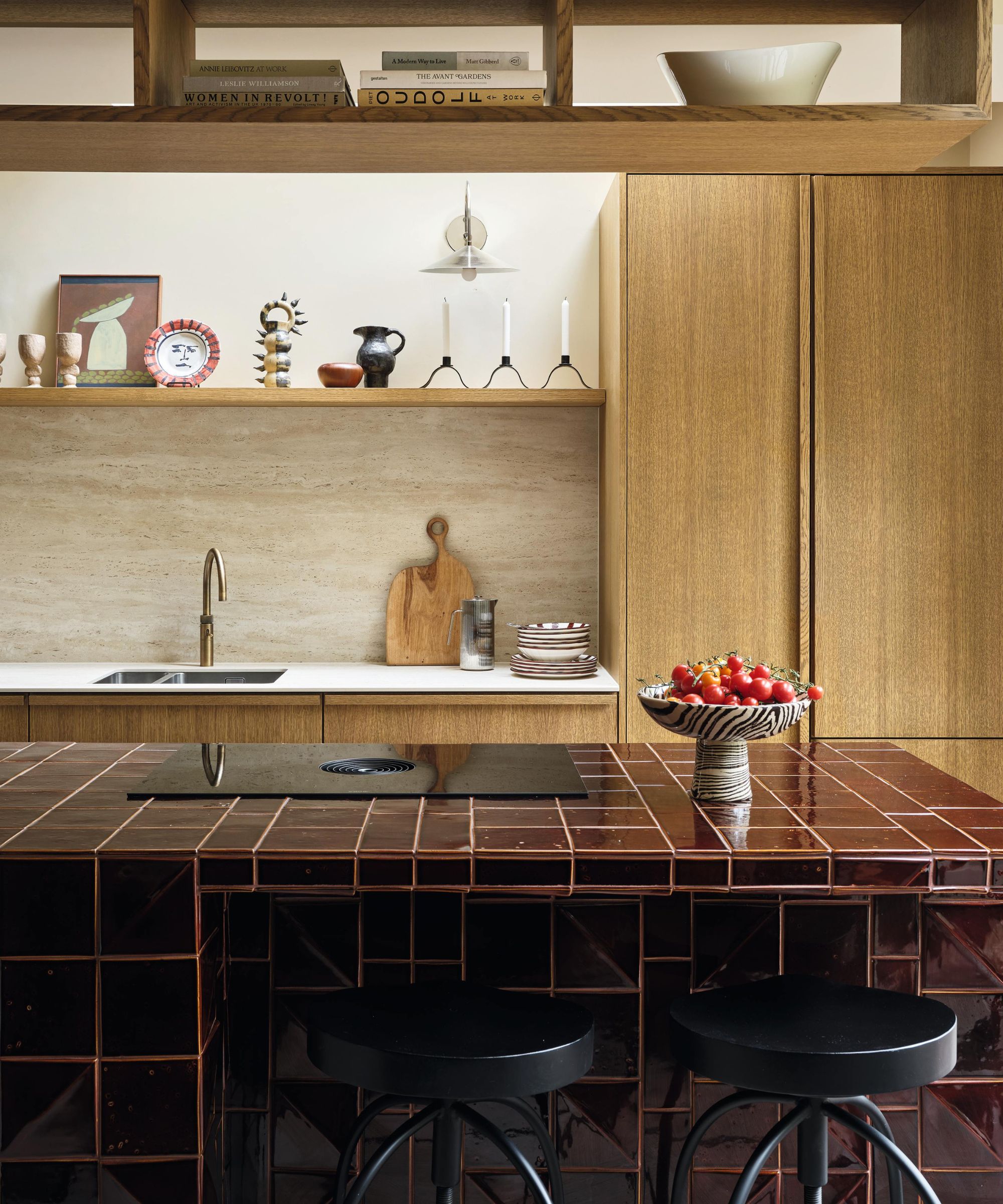 a wooden galley kitchen with a burgundy tiled kitchen island with black stools