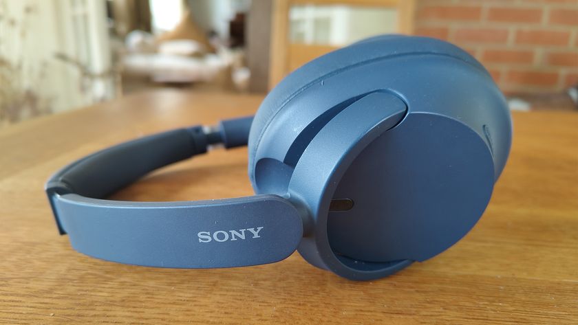 A pair of blue Sony WH-CH720N over-ear headphones placed on a wooden table.