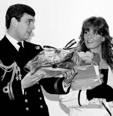 Prince Andrew wearing a naval uniform holding gifts smiling next to Sarah Ferguson 