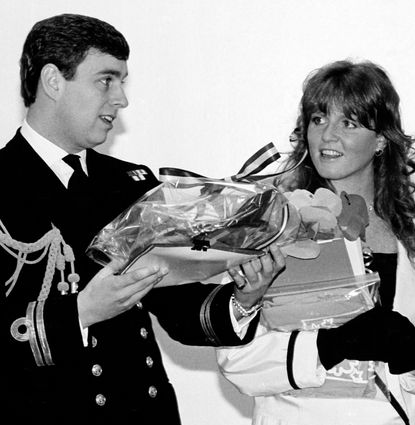 Prince Andrew wearing a naval uniform holding gifts smiling next to Sarah Ferguson 
