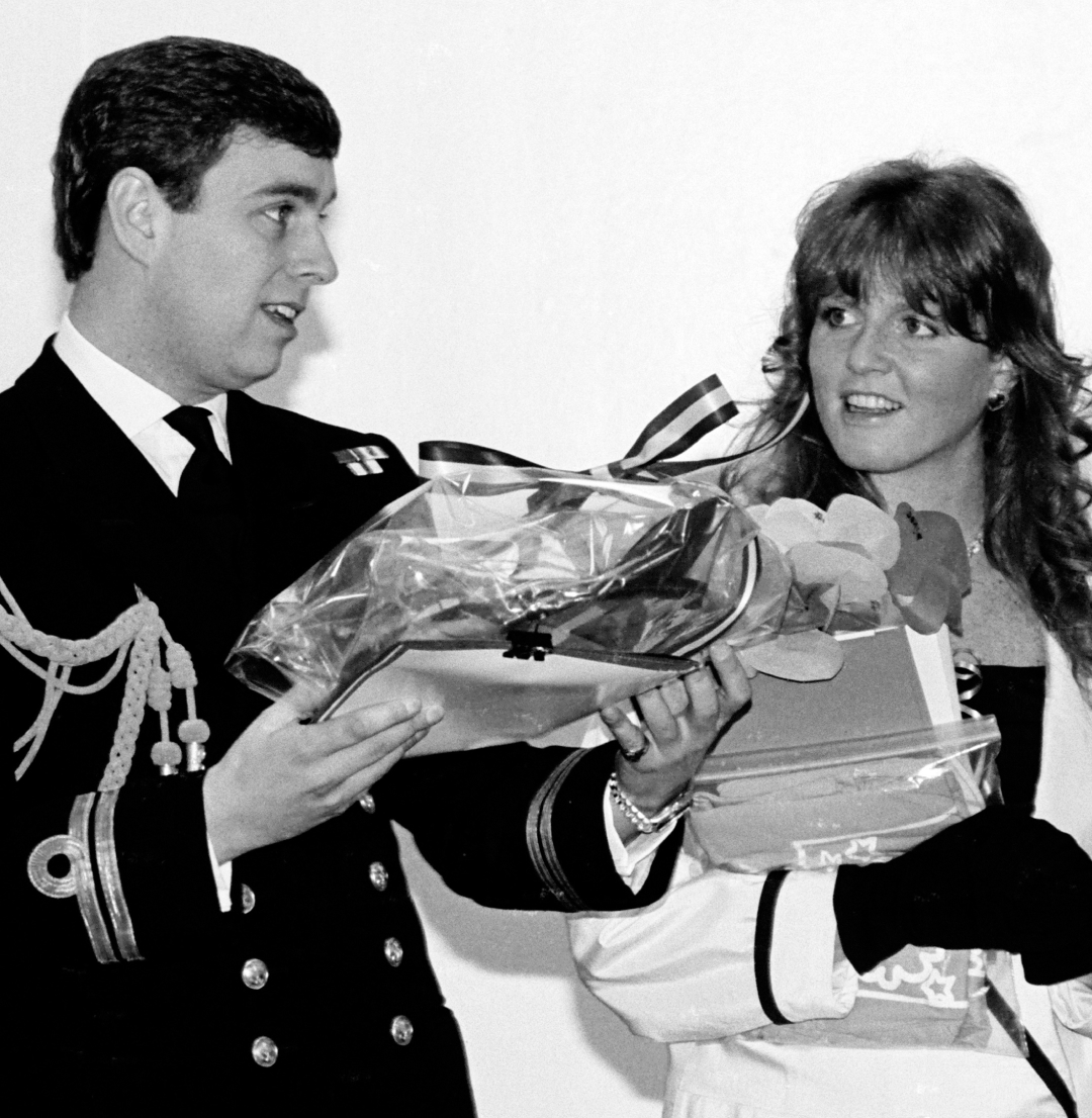 Prince Andrew wearing a naval uniform holding gifts smiling next to Sarah Ferguson 