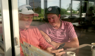Geno Bonallie and Joel Dahmen look at a phone in Waffle House