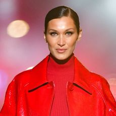 Bella Hadid wearing a red jacket and red top on the runway in 2021 for Michael Kors
