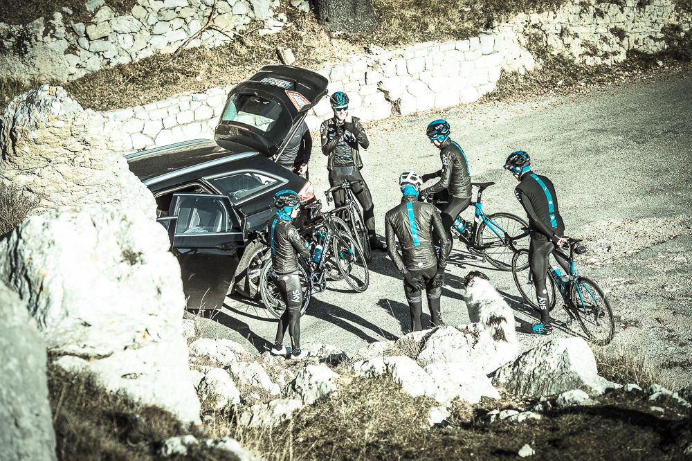 The riders are joined by a dog at the top of the Madone