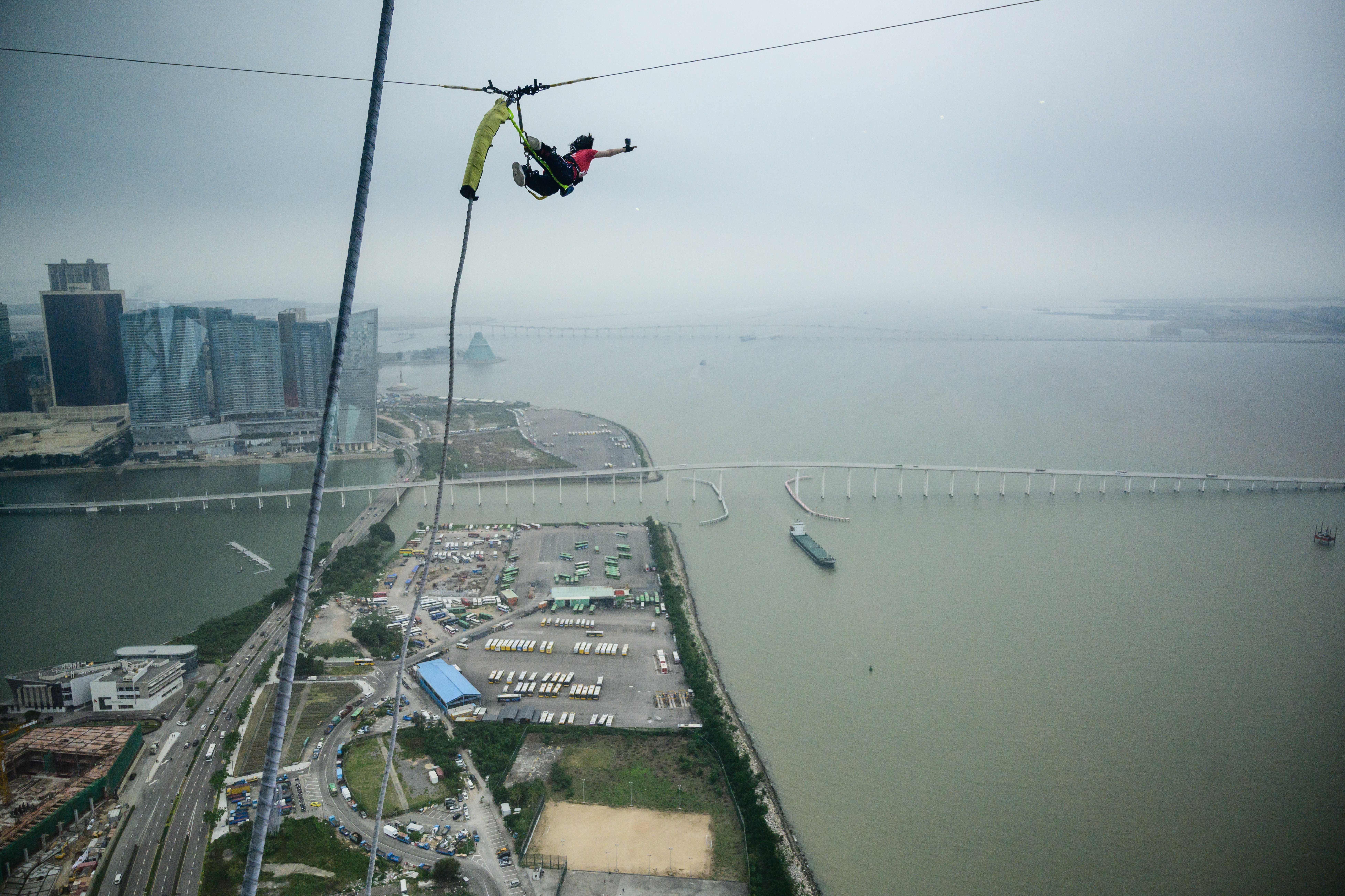 A woman bungee jumps from the top of Macau Tower on a cloudy day