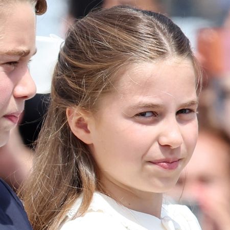 Princess Charlotte wearing a white dress with a matching bow in her long brown hair attending Trooping the Colour 2026 with the Royal Family