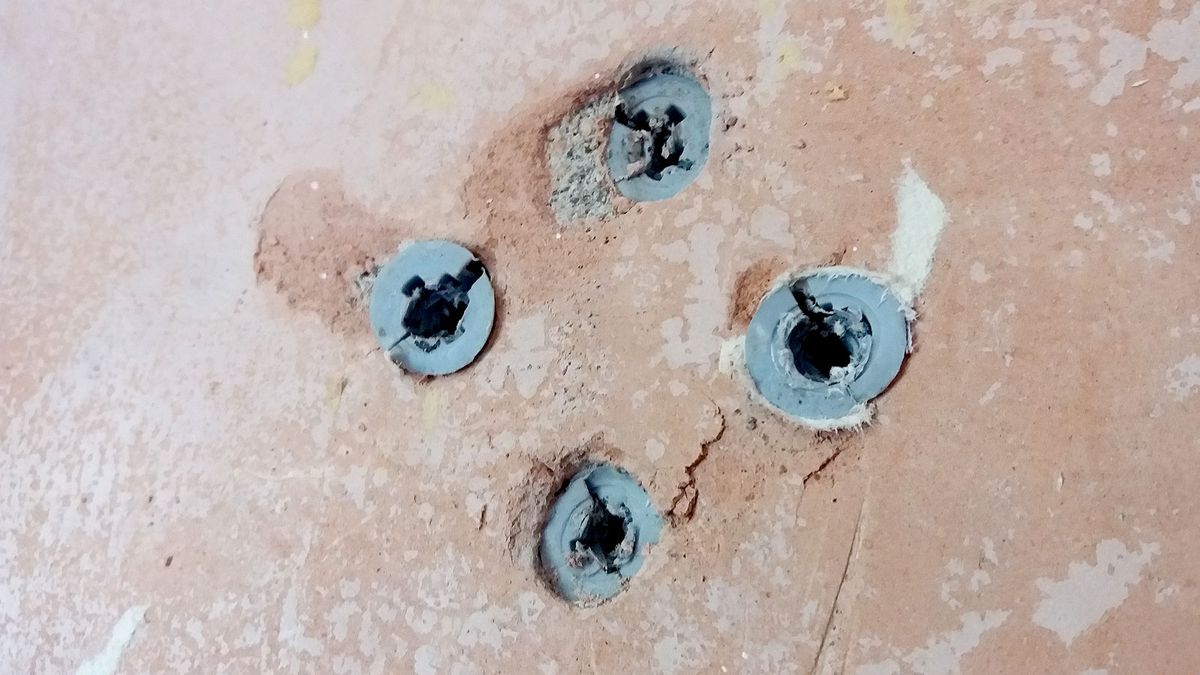 Close up of battered grey Rawl plugs in bare plaster wall