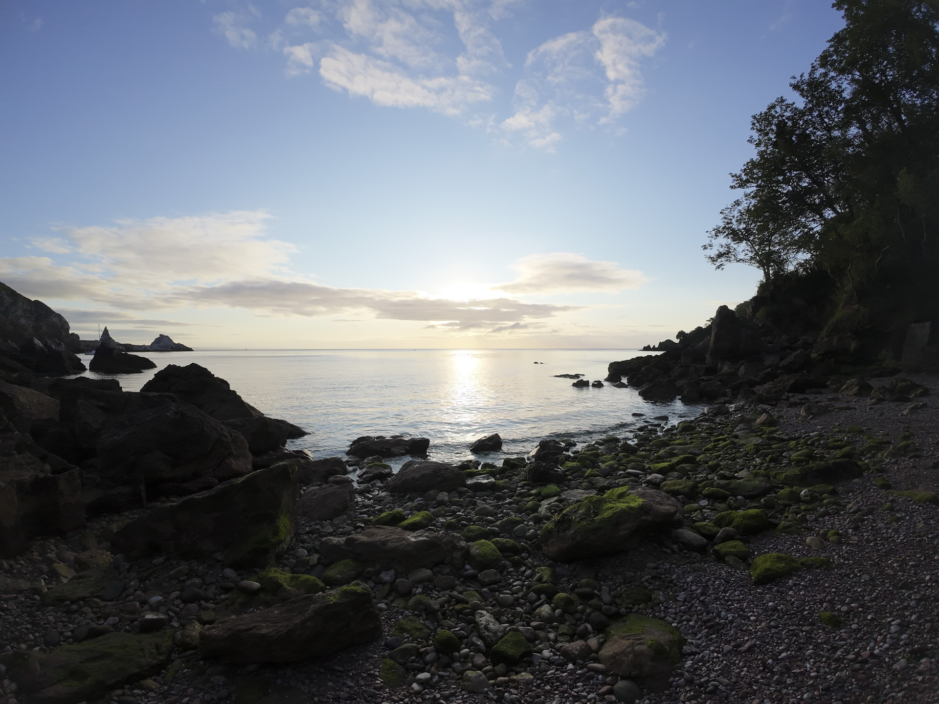 Early morning on a rocky beach with sunrise and calm seas