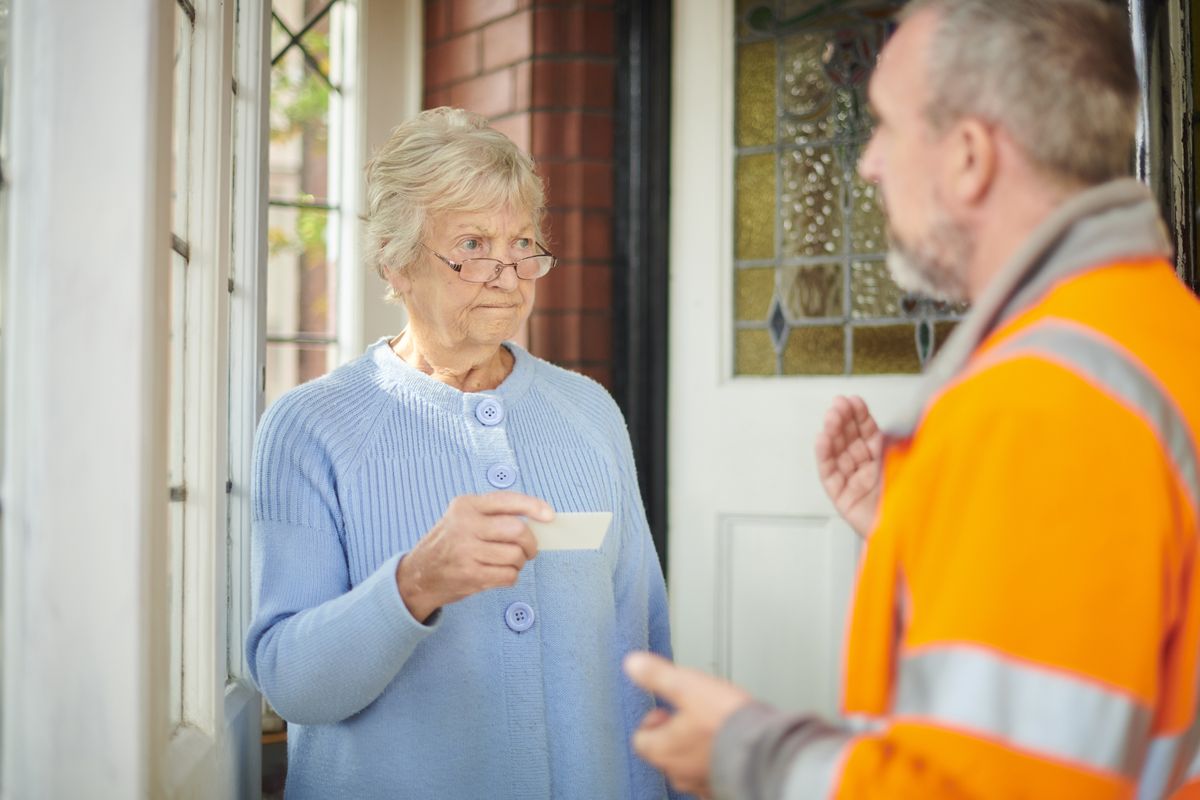 a woman looking sceptically at a builder on the doorstep