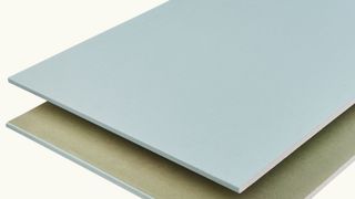 Green moisture resistant plasterboard at an angle on plain background