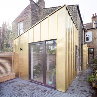 Single-storey extension clad in gold zinc alloy