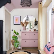 Hallway with pink shoe storage and round mirror