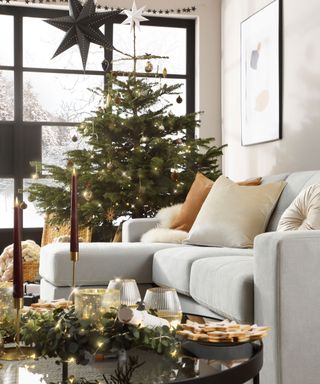 A grey corner sofa and black coffee table in a Christmas-decorated living room