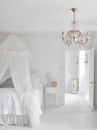 All white bedroom with canopy bed and chandelier