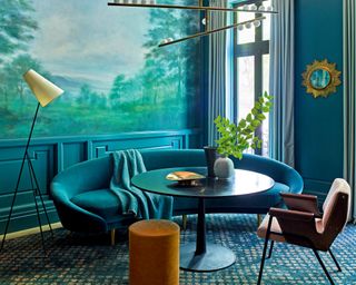 blue living room with mural, blue curved sofa and pink armchair
