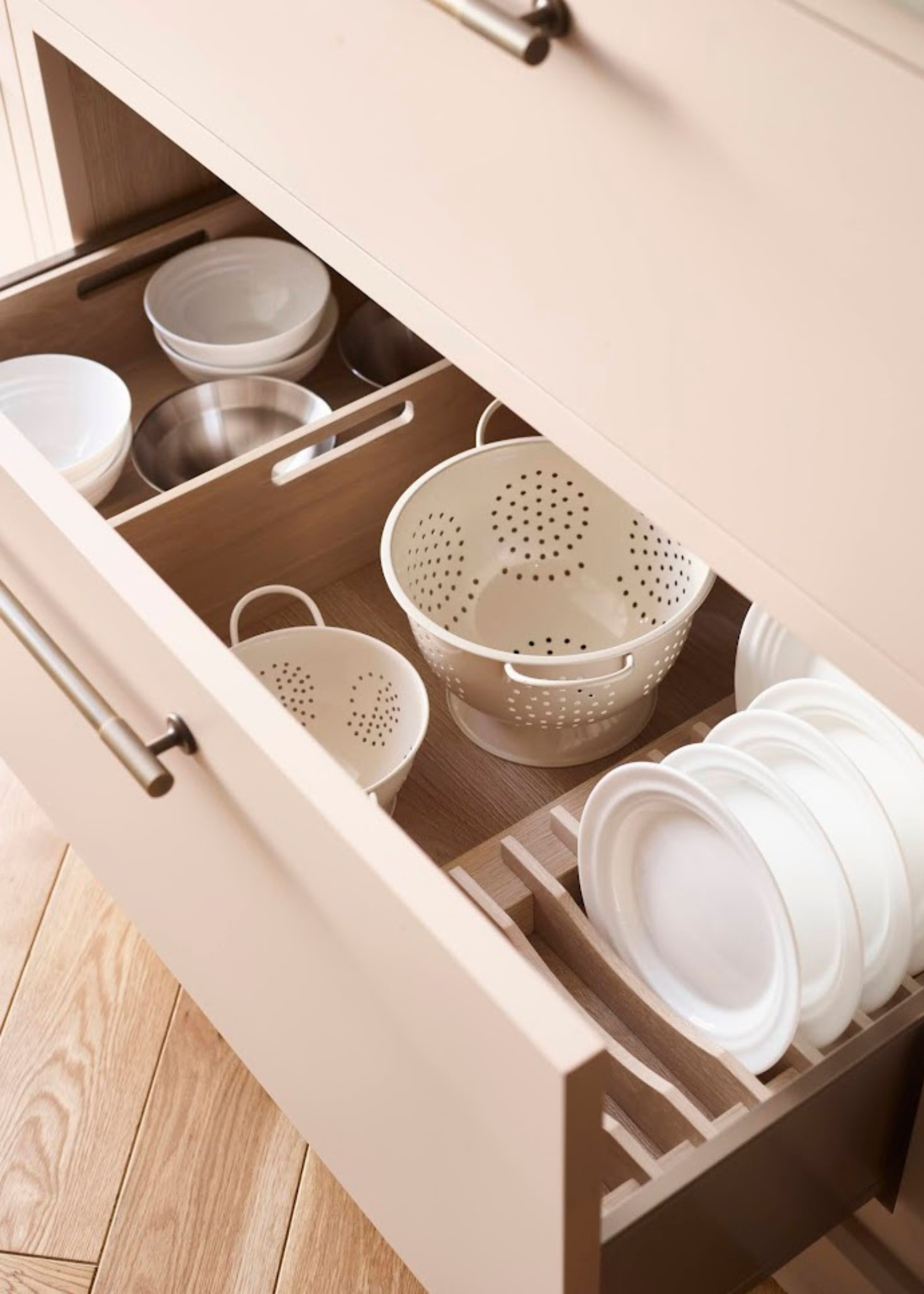 A deep wood pan drawer with dividers for different kitchen equipment and a plate rack