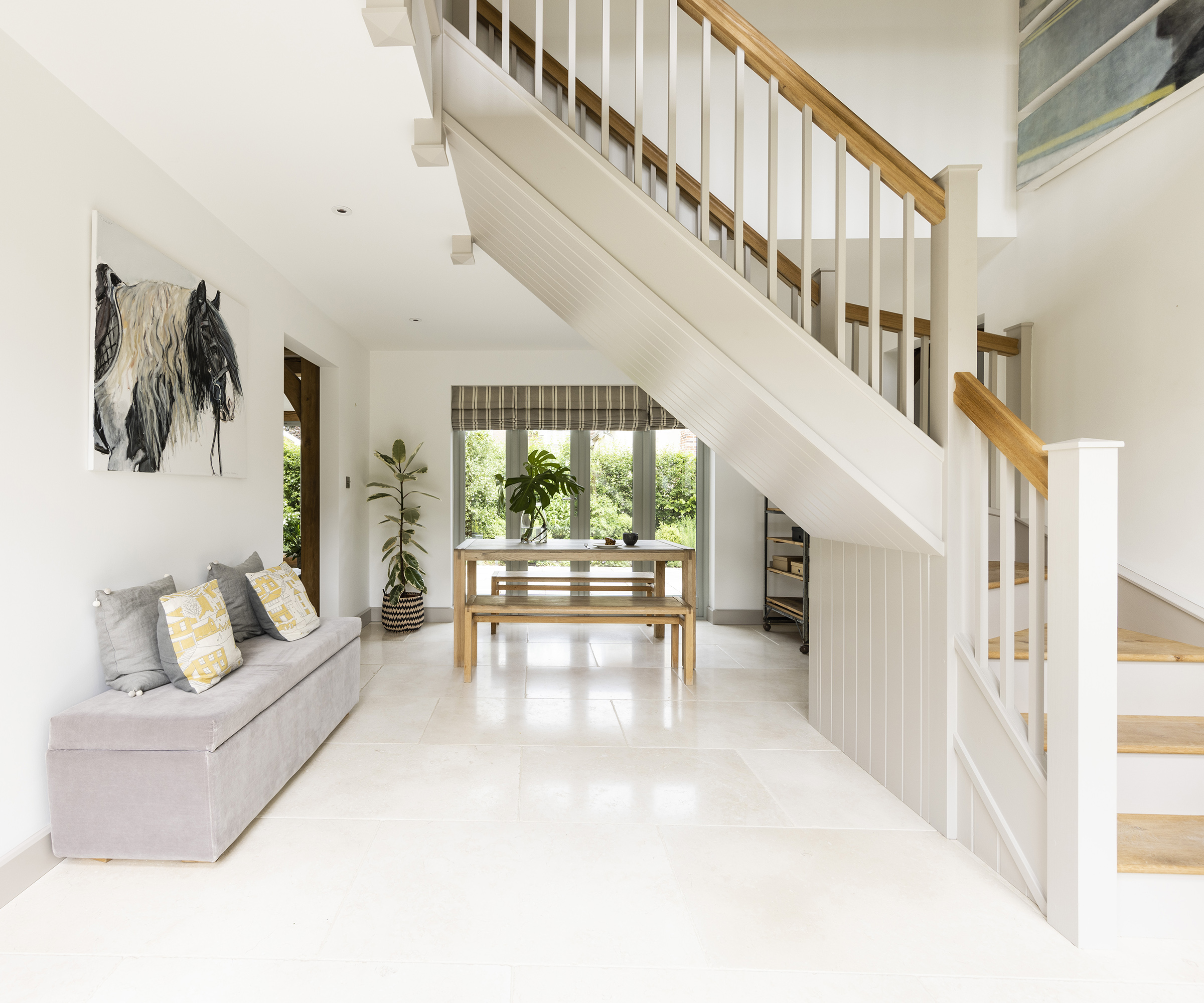 A large hallway/entrance hall with light tiled floor and lots of natural home