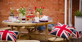 Circular wooden picnic table with Union Jack cushions and union jack decorations