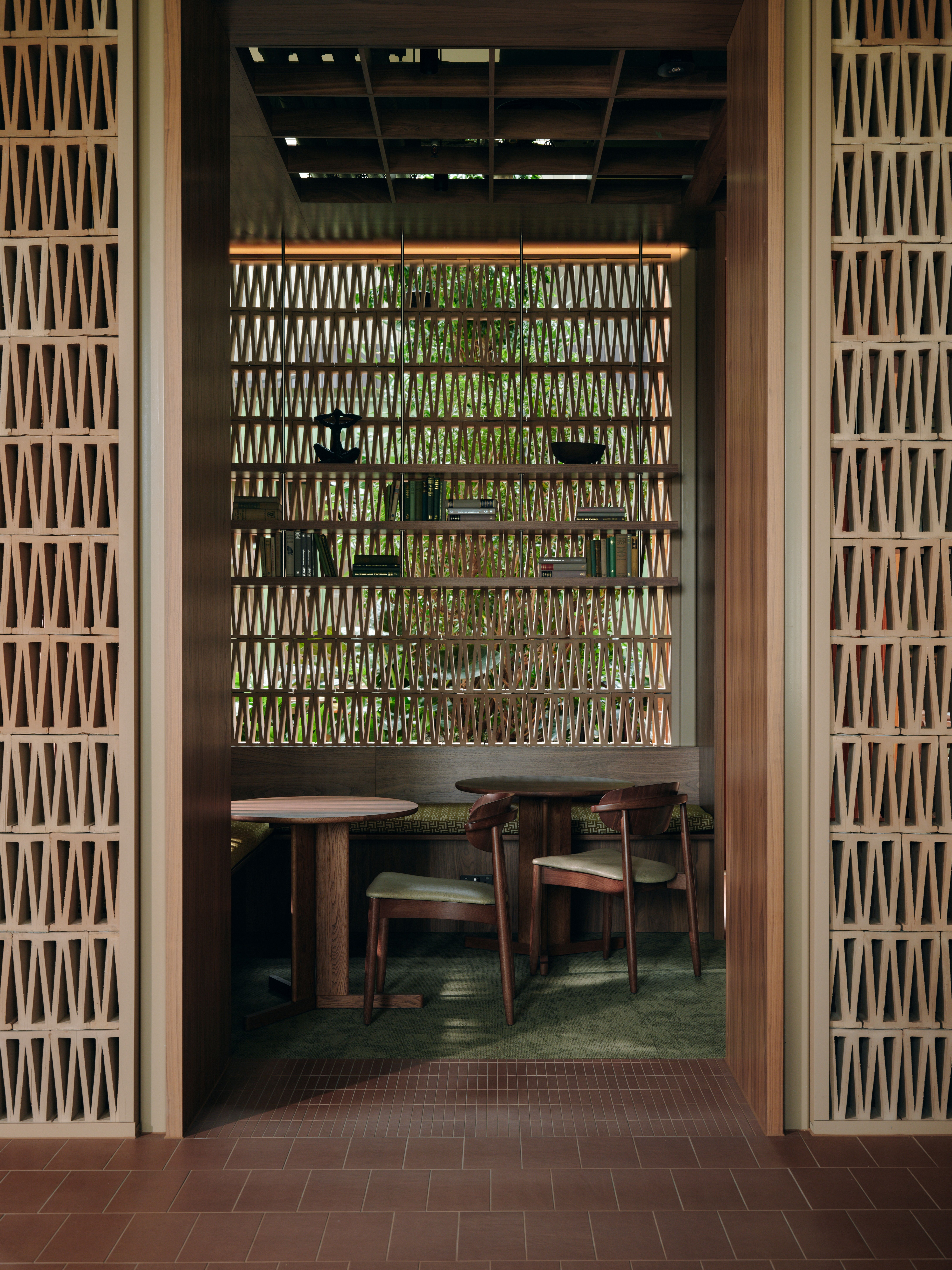 A series of interior shots of a workspace designed with terracotta-hued checkered floors, coffered ceilings in wood and back-lit blocks, pendant, see-through lighting, mid-century furniture, 