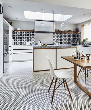 Vinyl tile flooring in a white kitchen with large patterned tile splashback, kitchen island, dining table and handleless cabinets