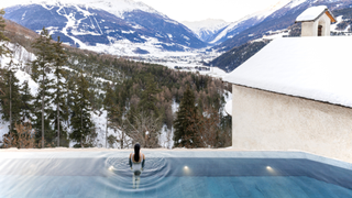 A woman looks out across the mountains from an infinity pool