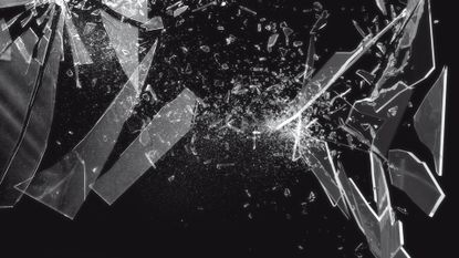 Shattered glass fragmenting into a multitude of sharp splinters pictured against a black backdrop.