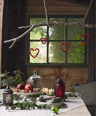 Rustic heart shapes made from berries on a branch hanging over the festive Christmas table.