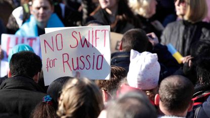 Protesters hold up signs Feb. 26 requesting that Russia be banned from the SWIFT transaction system