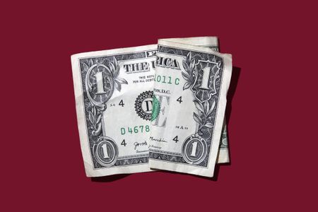 single US dollar bill against a deep red background