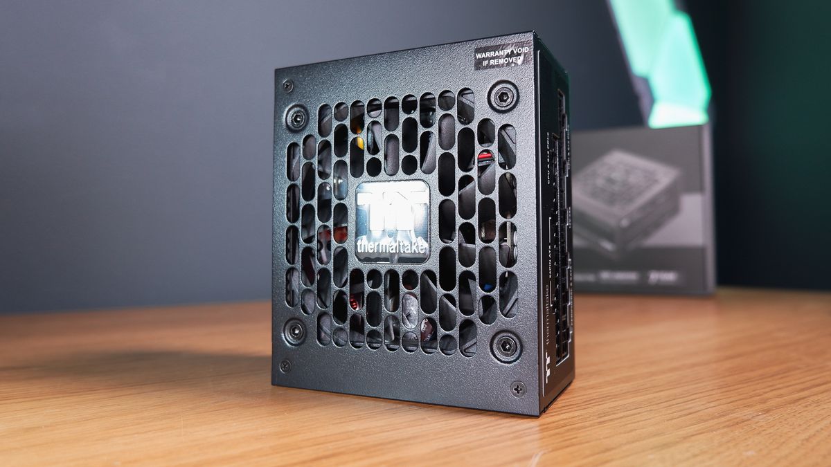 A compact gaming PC on a desk with various parts on show.