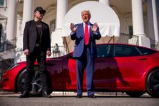 Donald Trump accompanied by Elon Musk, speaks next to a Tesla