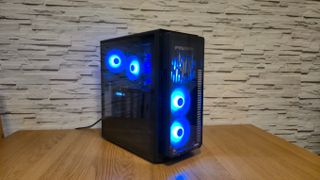 An Acer Predator Orion 5000 gaming PC sitting on top of a wooden surface infront of a white brick effect wall