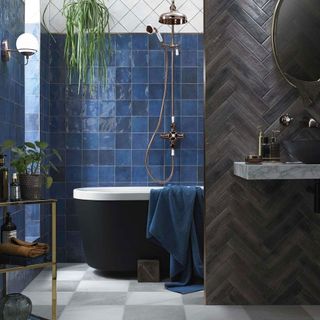 bathroom with ocean blue tiles wall and black bathtub and blue towel