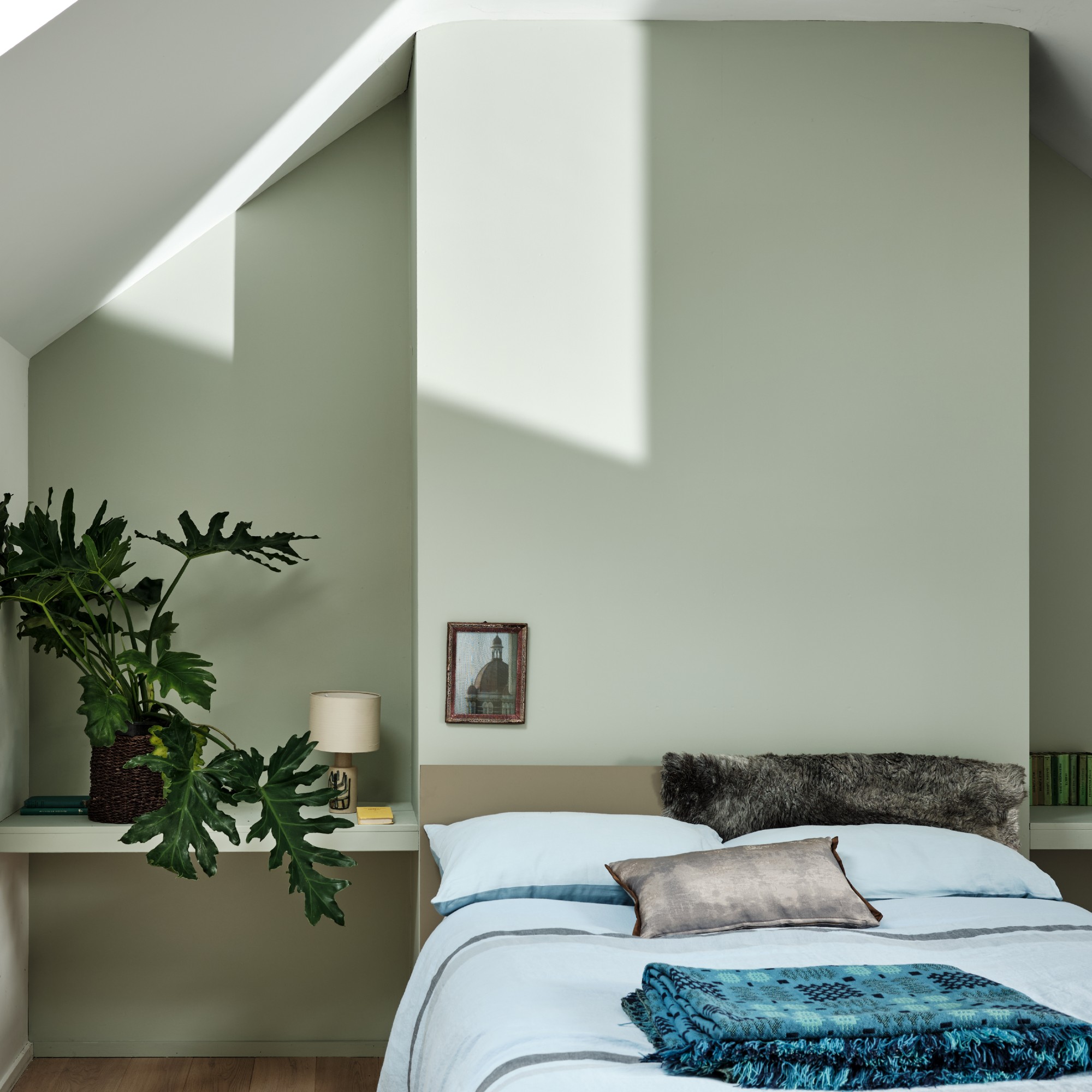 A calming bedroom with bedside tables built into alcoves painted in a soft green Farrow &amp;amp; Ball Mizzle shade