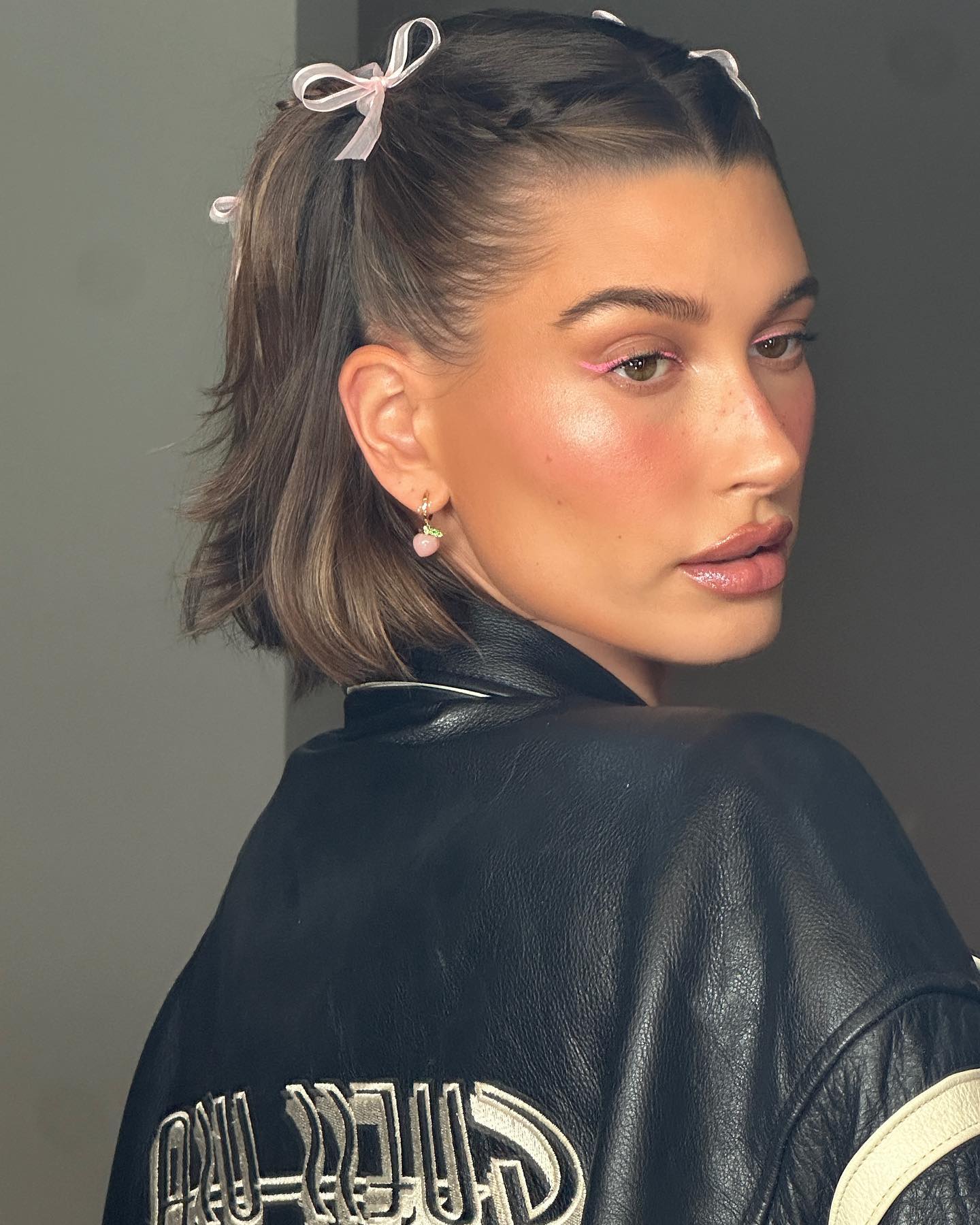 Hailey Bieber with short half up, half down hairstyle with braids and ribbons