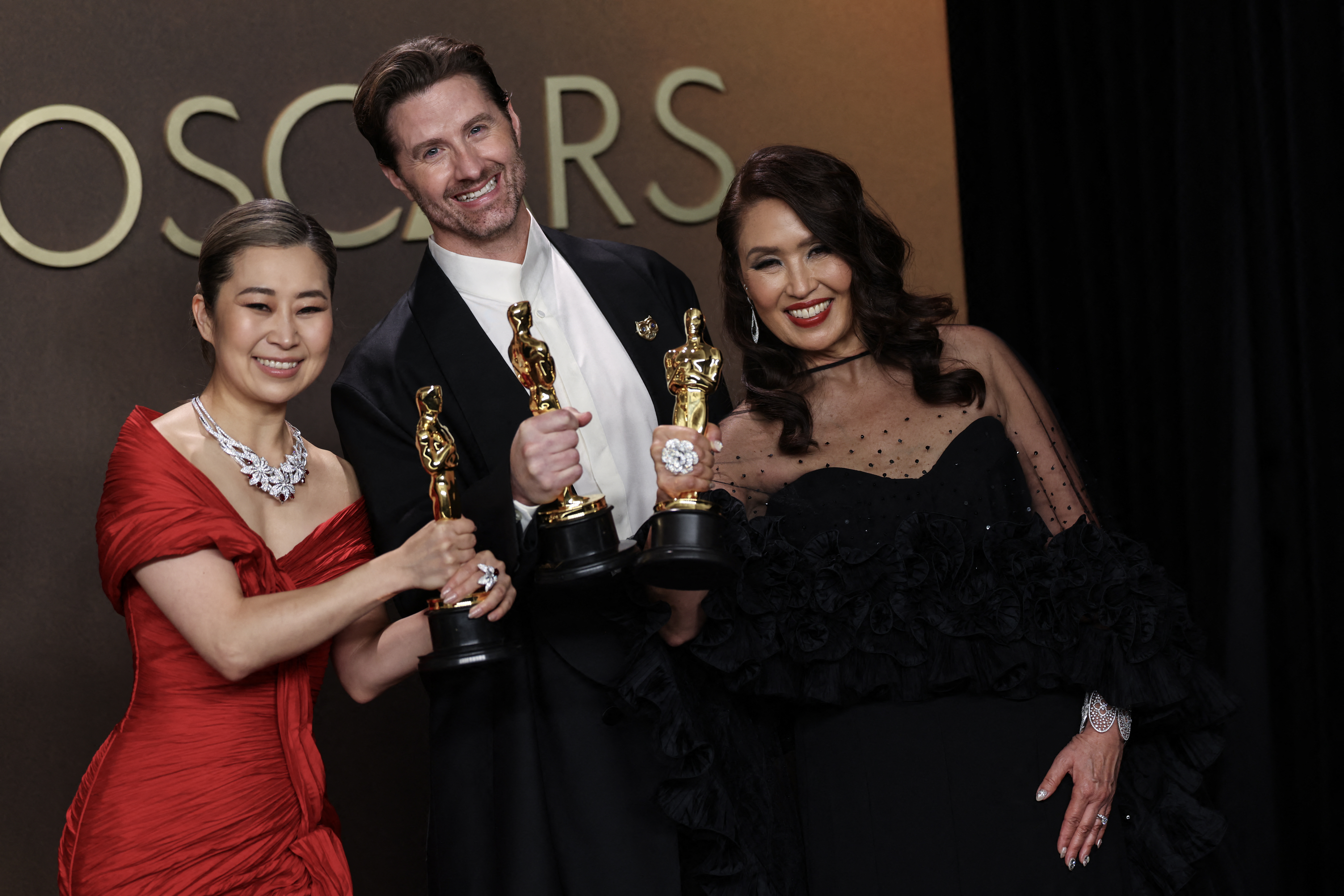 South Korean-Canadian storyboard artist and writer Maggie Kang, US film director Chris Appelhans, and film producer Michelle Wong pose in the press room with the Oscar for Best Animated Feature Film for "KPop Demon Hunters" during the 98th Annual Academy Awards at the Dolby Theatre in Hollywood, California on March 15, 2026