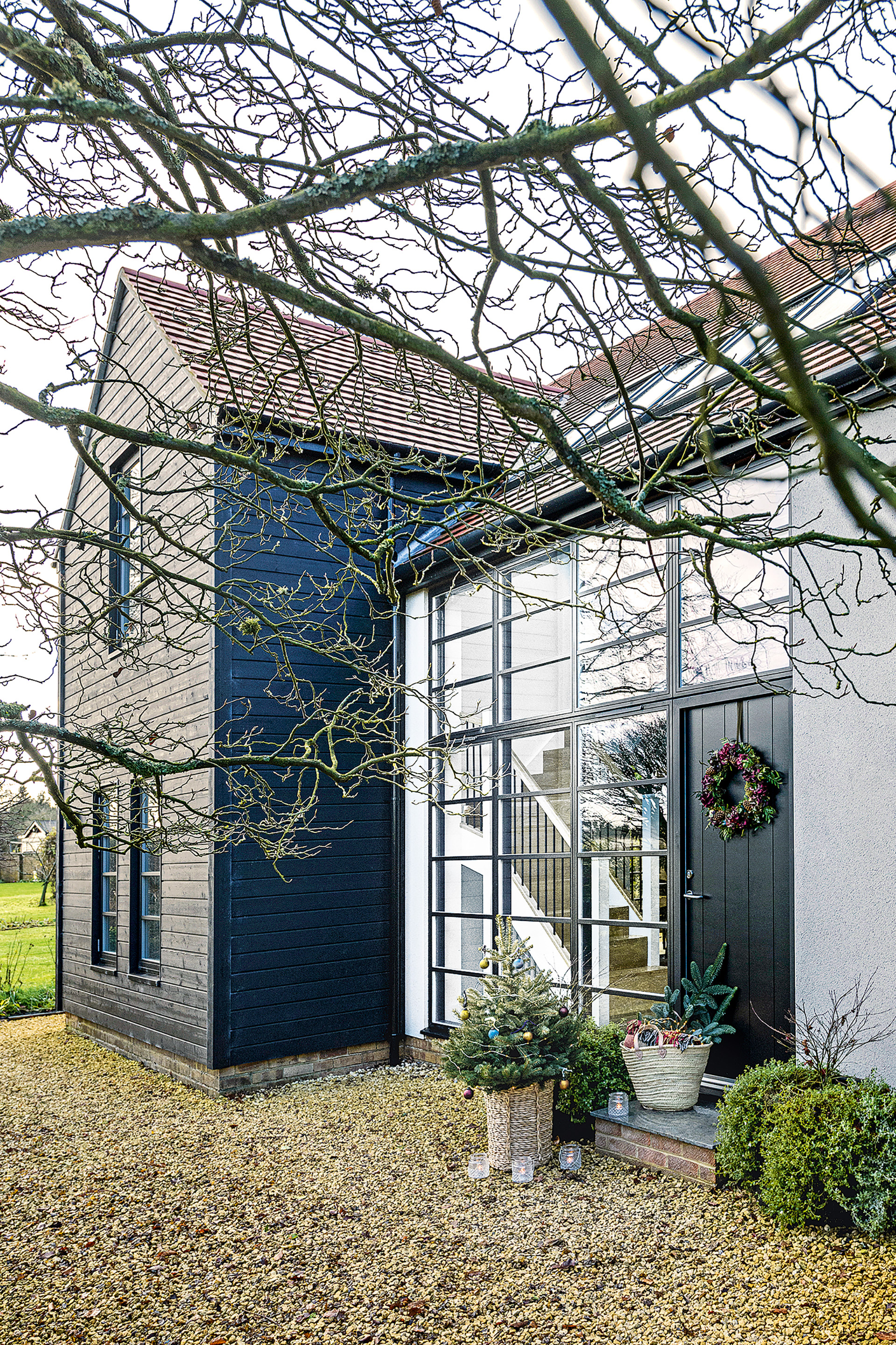 exterior of remodeled bungalow with full height glass wall and black cladding in winter