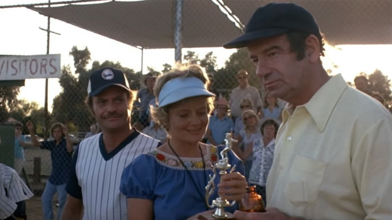 Joyce Van Patten handing a small trophy to Walter Matthau as Vic Morrow looks on in The Bad News Bears