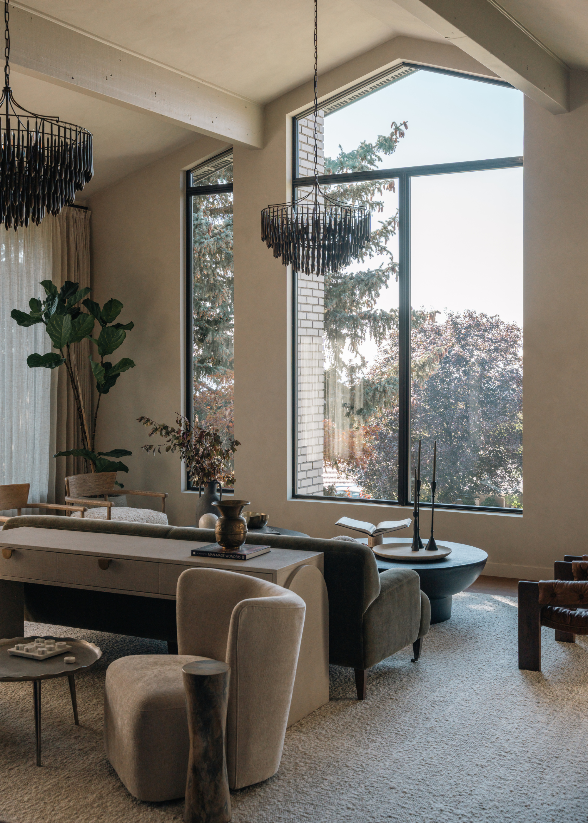 A Scandi minimalist living room with large windows, a two-sided lounging layout, and a large fiddle leaf fig plant