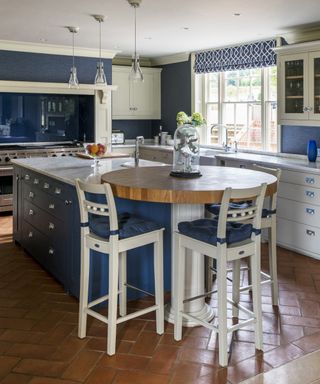 A kitchen with terracotta floor tiles, blue cabinets and white details