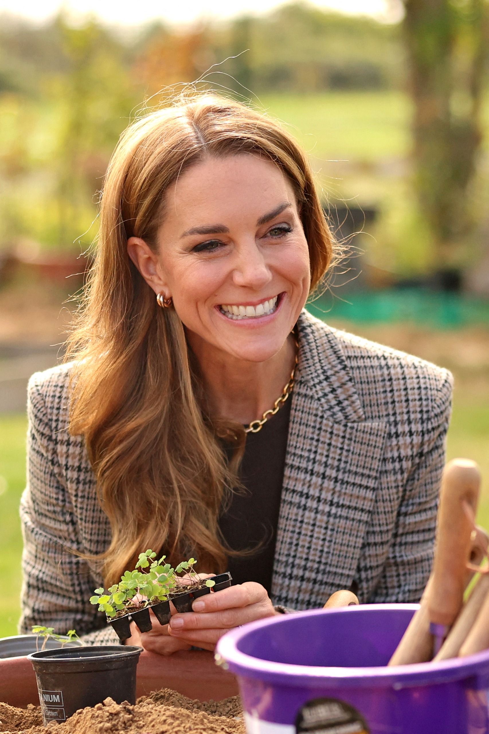 Princess Kate wearing a blazer and holding a pot with herbs
