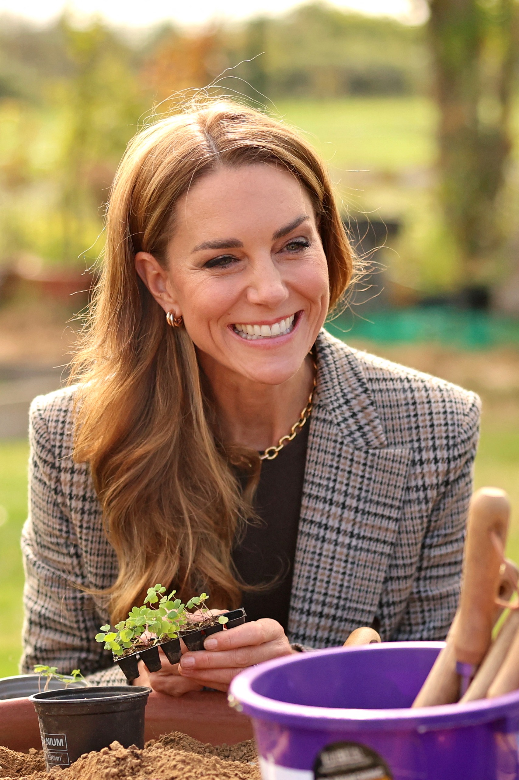Princess Kate wearing a blazer and holding a pot with herbs