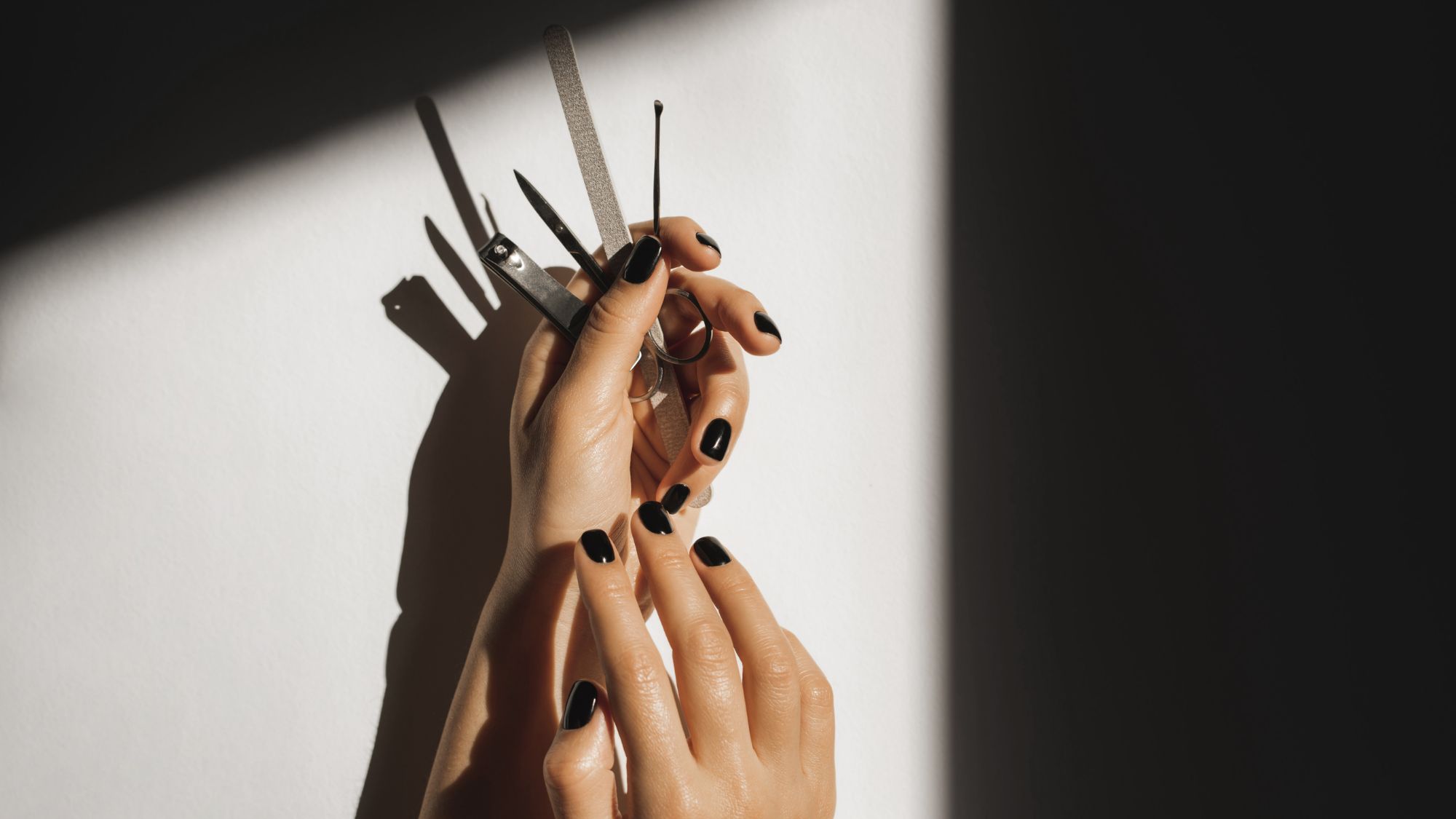 black painted nails holding manicure tools