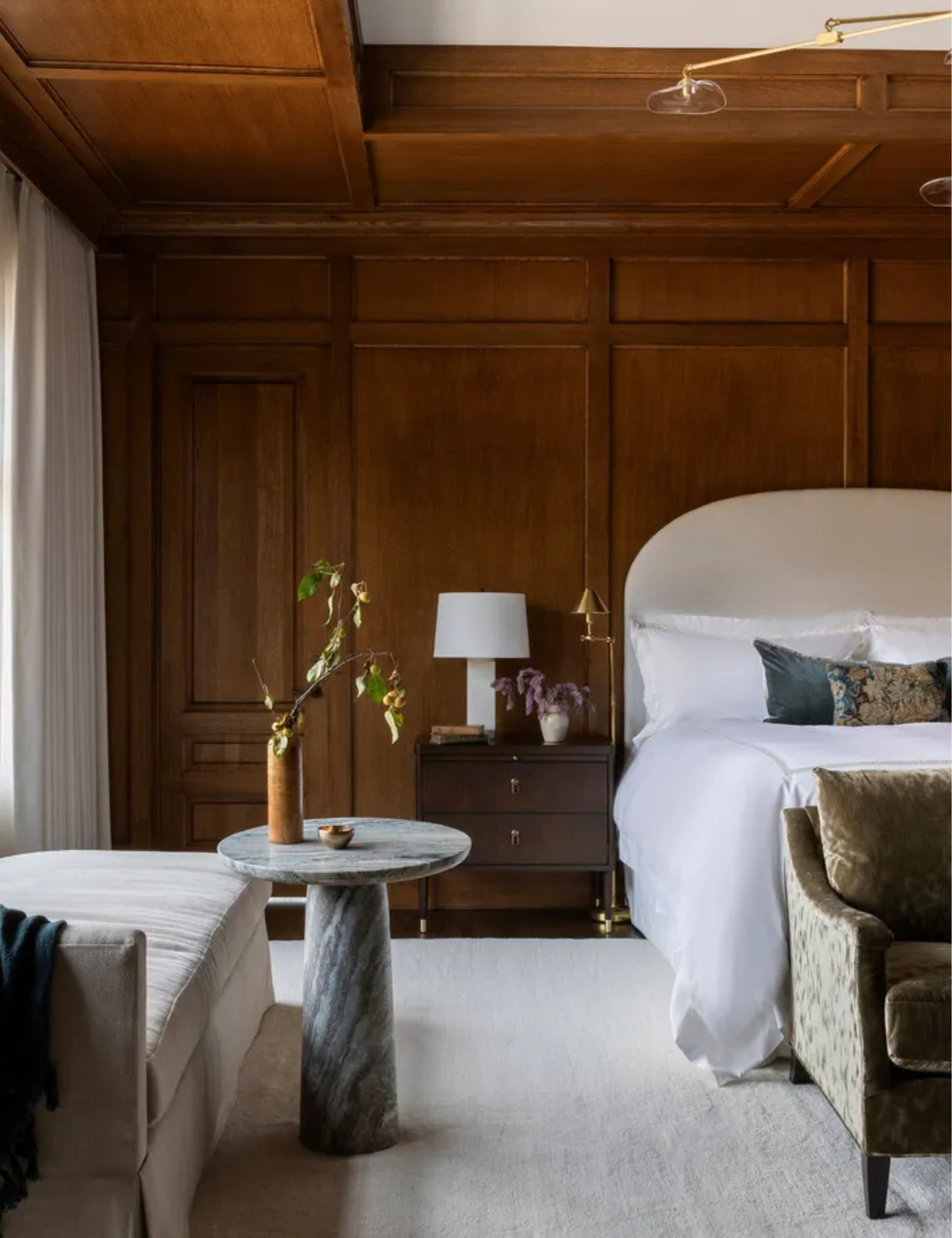 Dark wood panelled bedroom with large white headboard