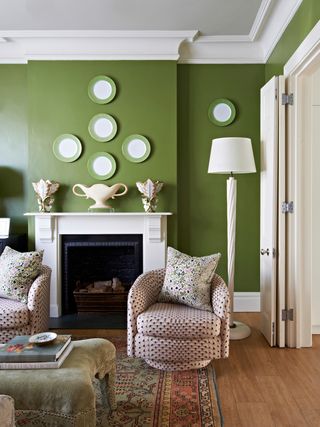 A living room with a deep green wall paint